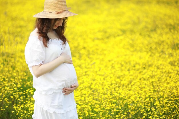 Zwangere vrouw in een jurk in een bloemenveld