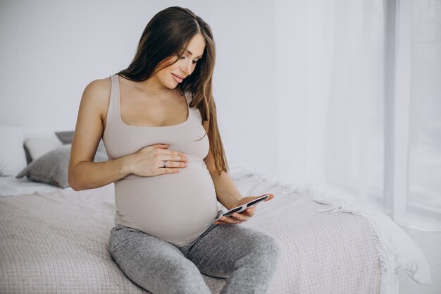 Zwangere vrouw met echografie foto zittend op bed