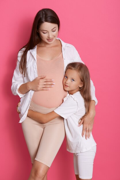 Zwangere vrouw met haar dochter het stellen