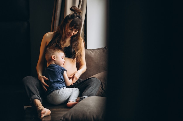 Zwangere vrouw met zoon zit bij het raam