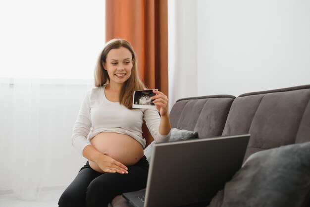 Zwangere vrouw videochatten met arts op laptop. professioneel medisch online overlegconcept.