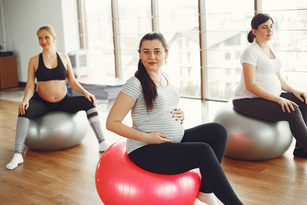 Zwangere vrouwen die yoga in een gymnastiek doen