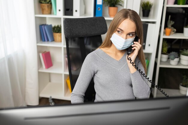 Zwangere zakenvrouw praten aan de telefoon terwijl het dragen van medische masker