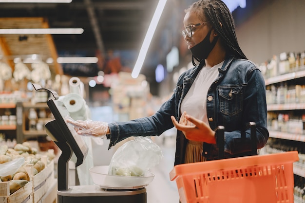 Zwart meisje in een masker koopt voedsel