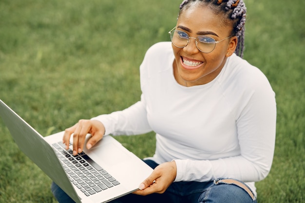 Zwart meisje in een zomerstad met laptop