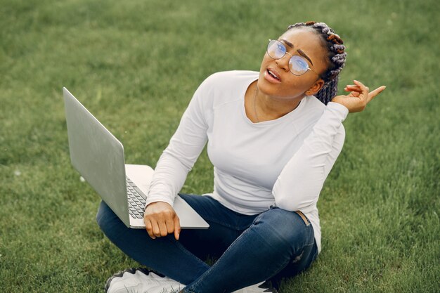 Zwart meisje in een zomerstad met laptop