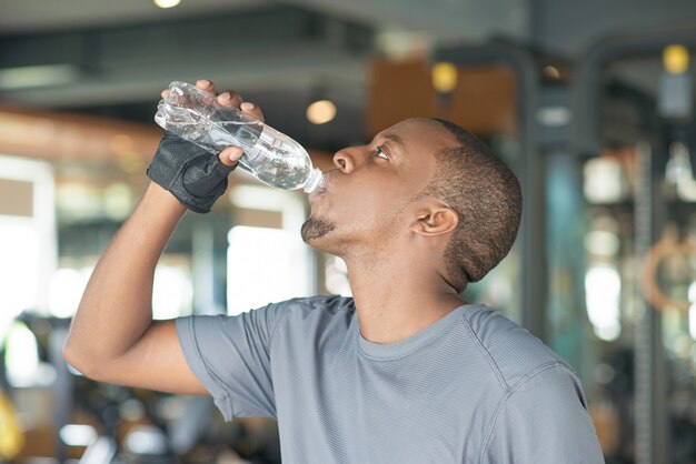 Zwart mensen drinkwater van fles in gymnastiek