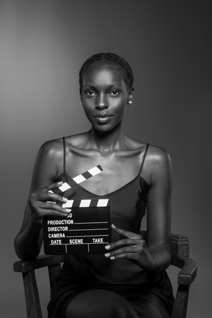 Zwart-wit portret van een vrouw met filmklapper in oude Hollywood-glamourstijl