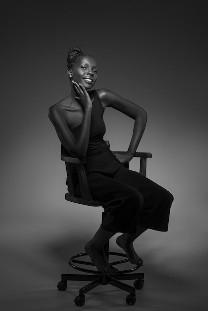 Gratis foto zwart-wit portret van een vrouw op een stoel in oude hollywood-glamourstijl