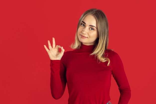 Zwart-wit portret van jonge blanke blonde vrouw op rode muur