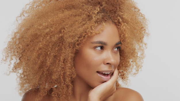 Zwartblond model van gemengd ras met krullend haar vroeg zich af of model haar gezicht naar rechts draaide