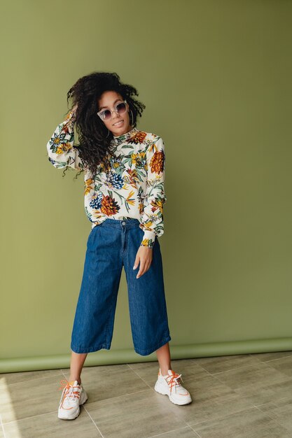 zwarte afro-amerikaanse vrouw in stijlvolle outfit jeans en blouse geïsoleerd op groen