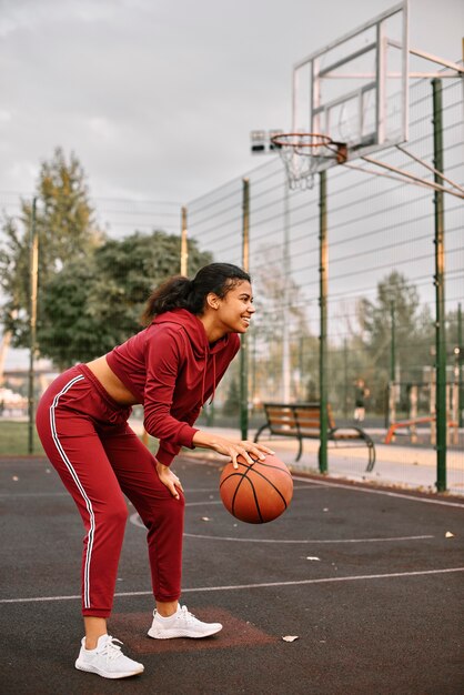 Zwarte Amerikaanse vrouw met basketbal op een veld