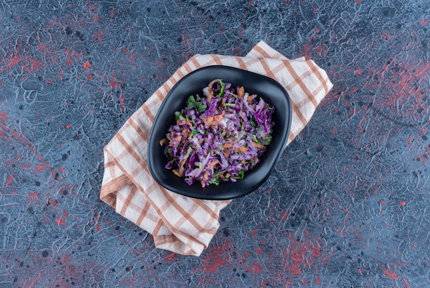 Zwarte diepe plaat met groentesalade op een tafelkleed