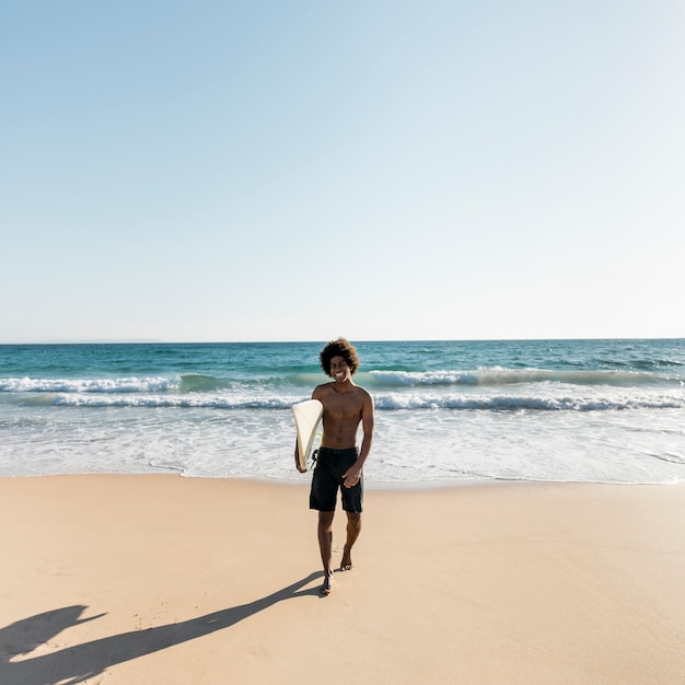 Gratis foto zwarte man gaat uit oceaan na het surfen