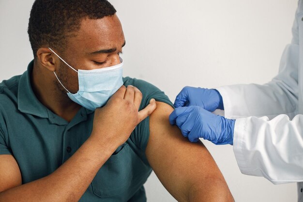 Zwarte man geïsoleerd op een witte achtergrond krijgt covid-vaccinatie