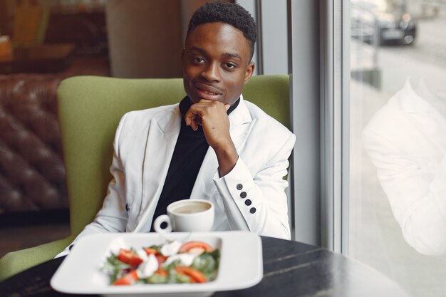 Zwarte man zit in een cafe en het eten van een groente salade