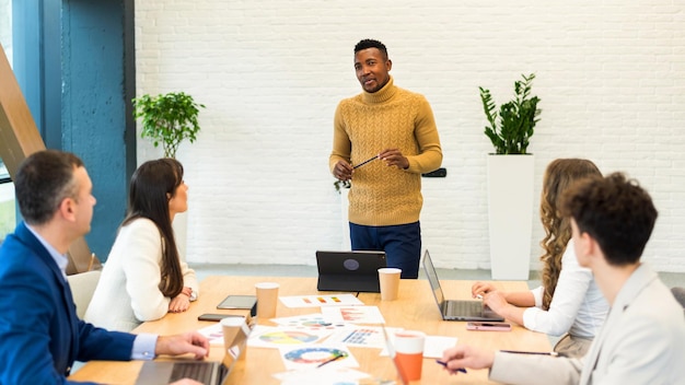 Gratis foto zwarte mannelijke teamleider op zakelijke bijeenkomst in een kantoor