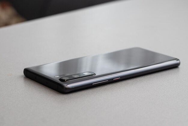 Zwarte moderne mobiele telefoon met leeg scherm op zwarte stenen tafel achtergrond. smartphone op oude donkergrijze vintage textuur achtergrond.
