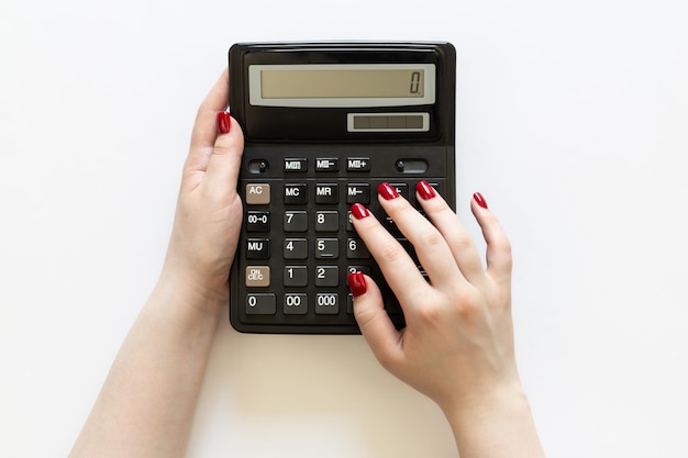 Zwarte rekenmachine in de handen van een vrouw op een witte achtergrond bovenaanzicht