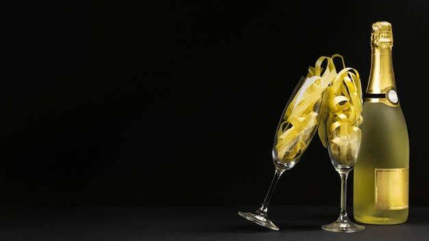 Zwarte scène met twee glazen en een fles champagne.