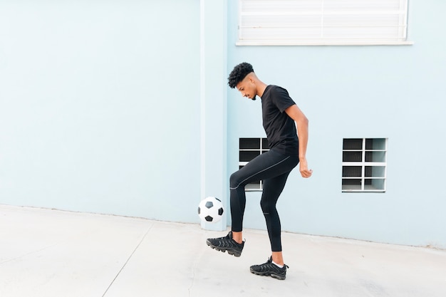 Zwarte sportman schoppen voetbal op de veranda