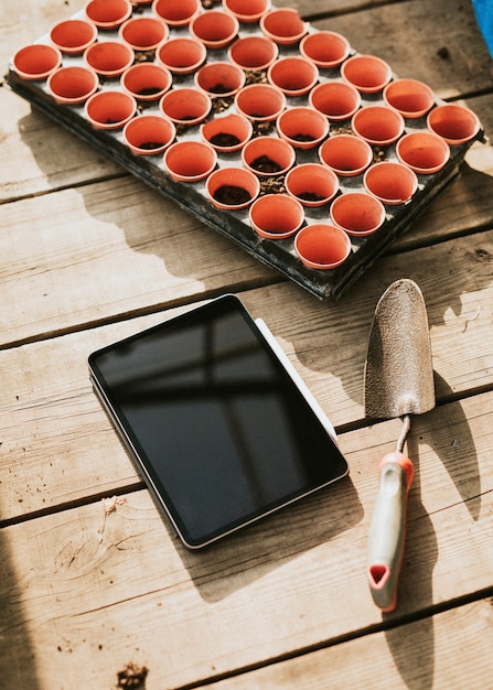 Zwarte tablet door een tuintroffel op een houten tafel