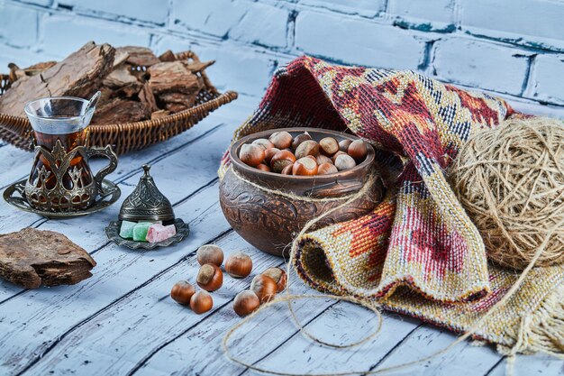 Zwarte thee in een traditionele glazen beker met snoepjes en een kom met hazelnoten op blauwe houten tafel