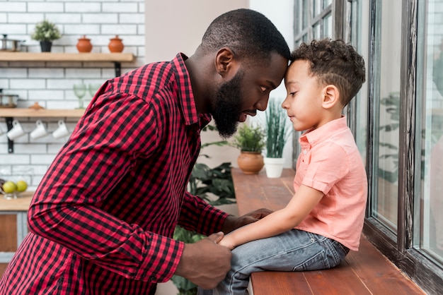 Gratis foto zwarte vader die hand van zoon op de vensterbank