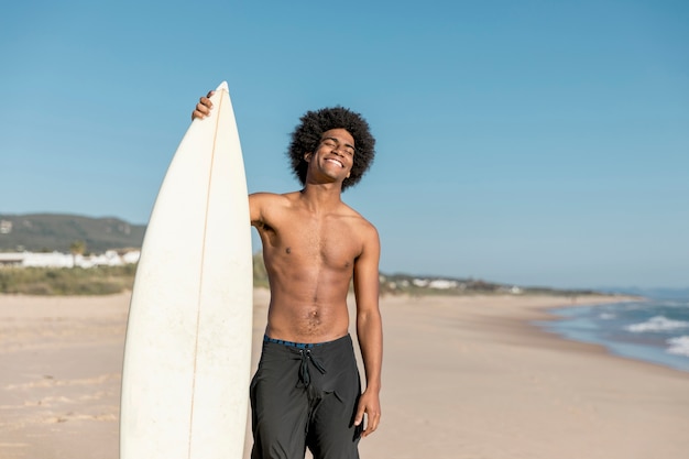 Zwarte volwassen surfer die met gesloten ogen glimlacht