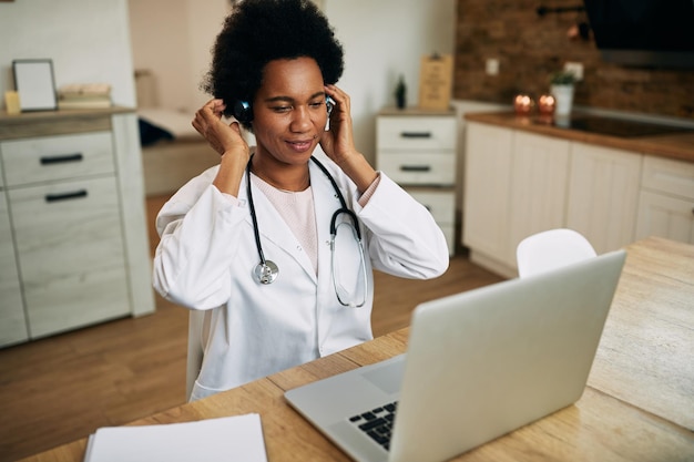 Zwarte vrouwelijke arts bereidt zich voor op videogesprek via laptop in haar kantoor