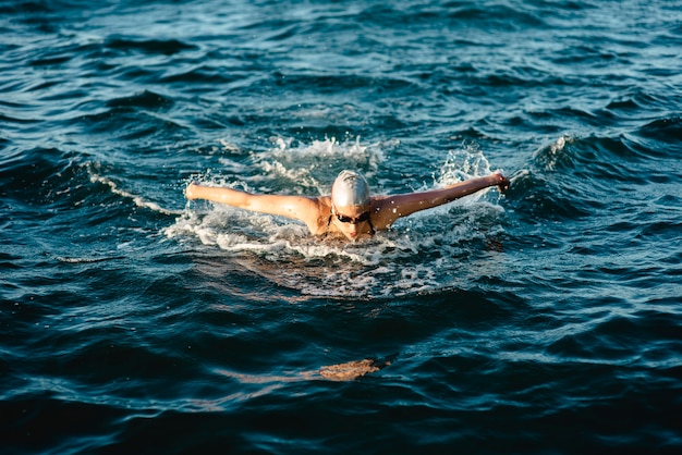 Zwemmer met pet en bril zwemmen in water