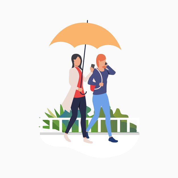Vrouwen lopen onder de paraplu en gebruiken smartphones